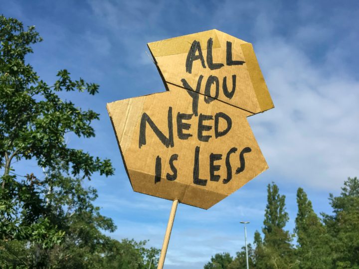 ‘All you need is less’ handwritten sign in a protest-like shape.